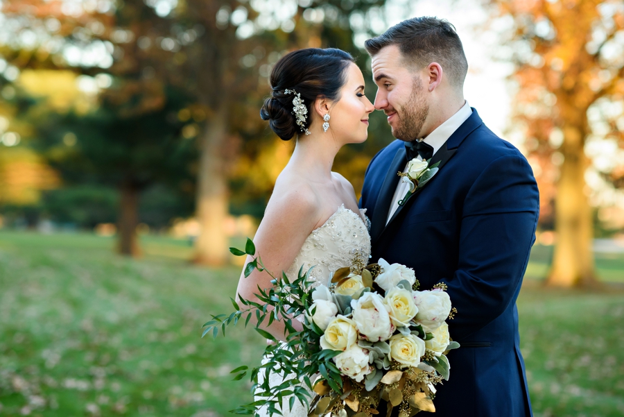 A newly married couple kiss outside in the fall light.